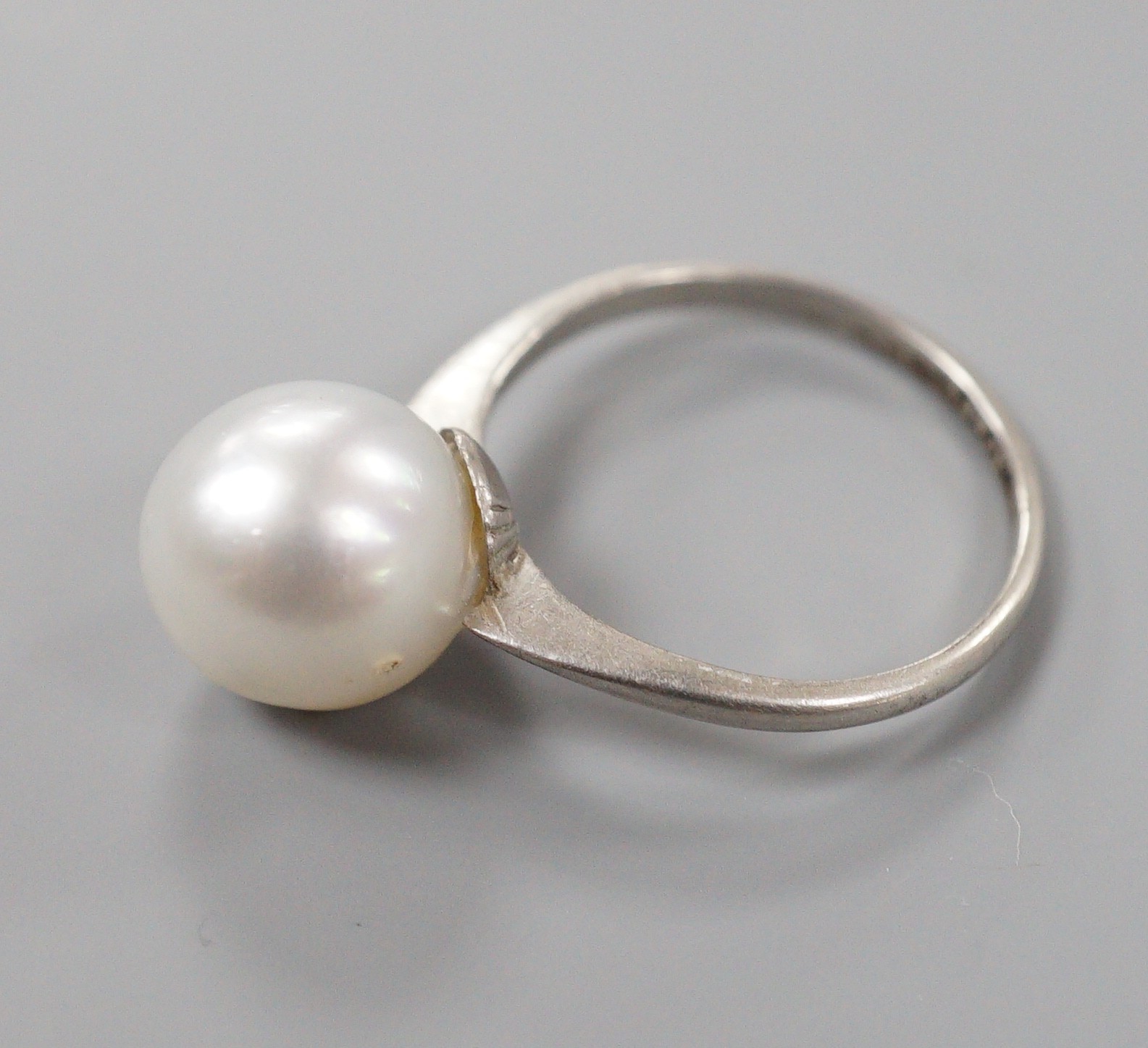 A white metal (stamped Plat) and single stone cultured pearl ring, size O, gross weight 4.1 grams.